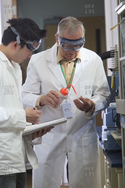Professor working with engineering student adding ethanol to sample tray in a laboratory