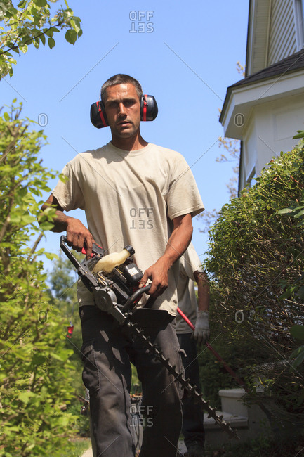 Landscaper with an electric weed trimmer and ear protectors