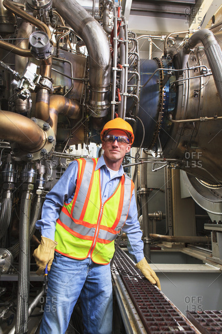 Engineer at fuel injection stage of gas turbine which drives generators in power plant while turbine is powered down
