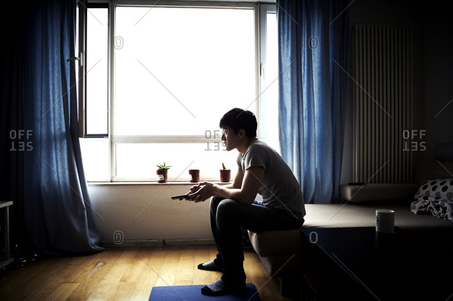Beijing, China - February 8, 2012: Man sitting on sofa holding television remote in Beijing, China