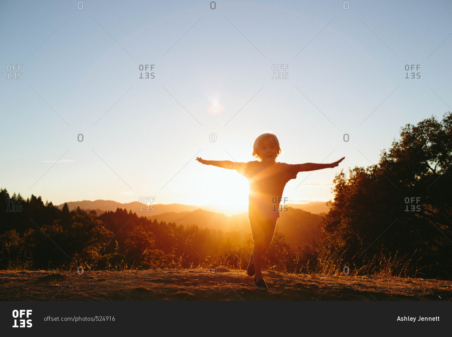 Boy backlit by sun in rural hills