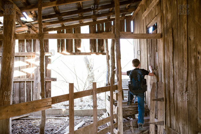 Boy exploring an abandoned cabin in the wilderness