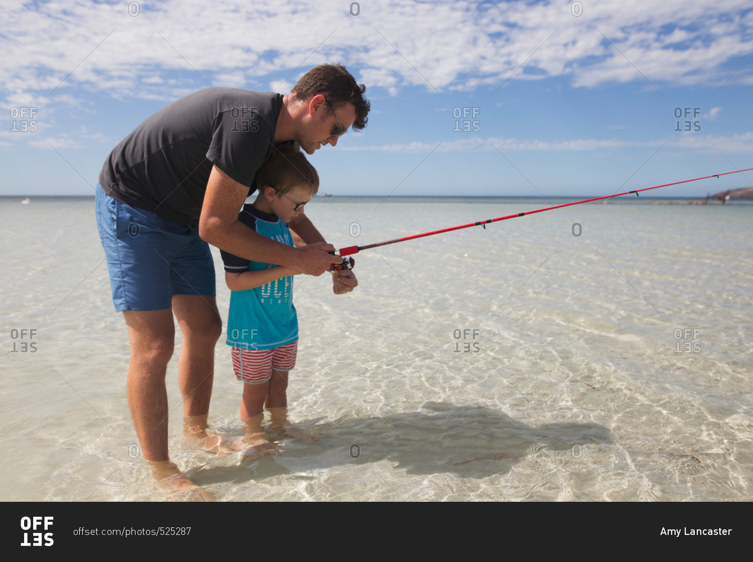Father showing his son how to use fishing reel