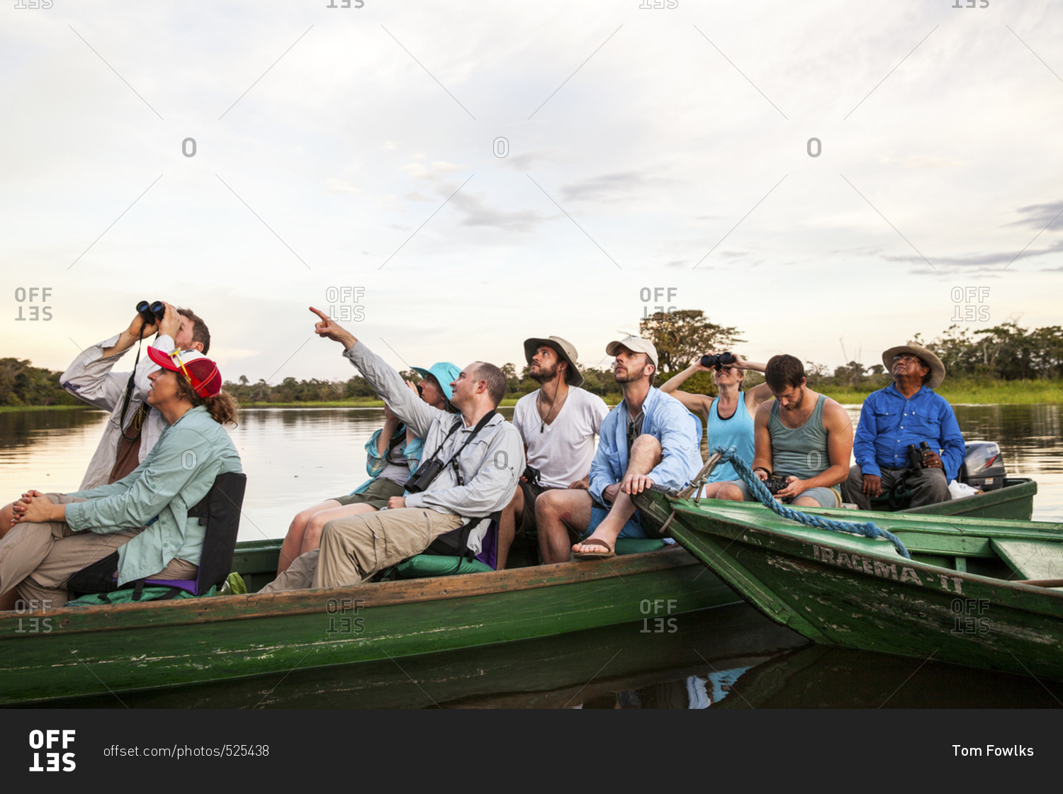 Amazonas, Brazil - February 25, 2015: Group of tourists spotting a bird in the jungle canopy from their canoe on the Amazon River