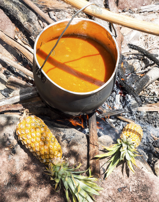 Soup and pineapples cooking over fire