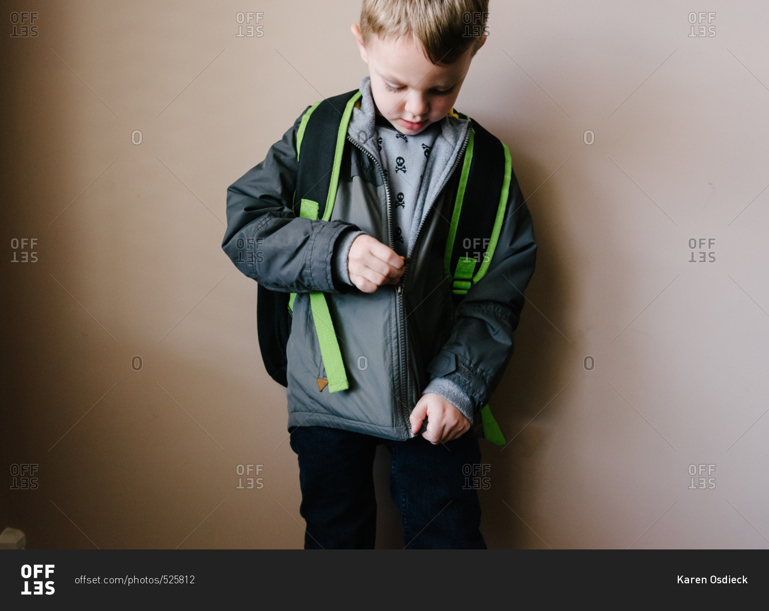 Boy with backpack zipping his jacket