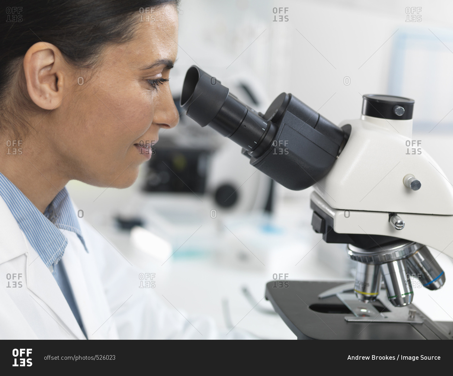 Female scientist viewing sample slide for clinical test in laboratory