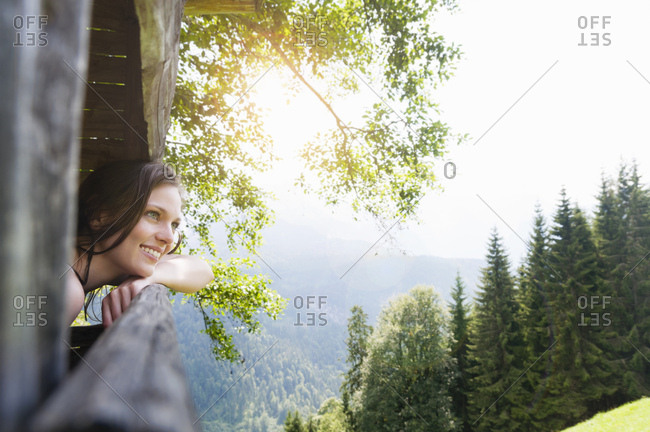 Side view of mid adult woman looking out of tree house at view, Tegernsee, Germany