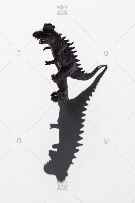 Toy dinosaur with a long shadow
