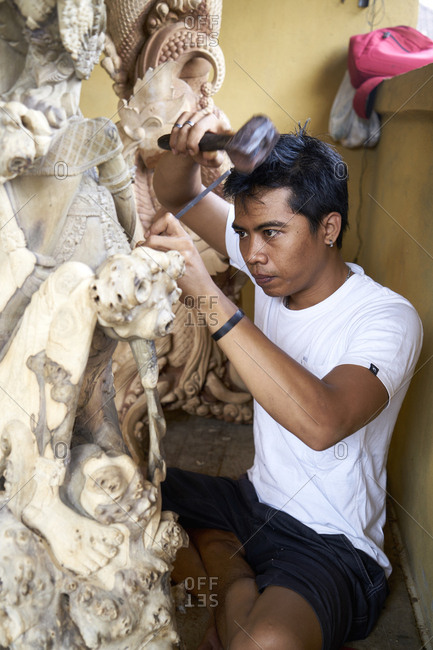 Bali, Indonesia - February 19, 2017: Balinese man hand-crafting wood relief carvings and wood sculptures