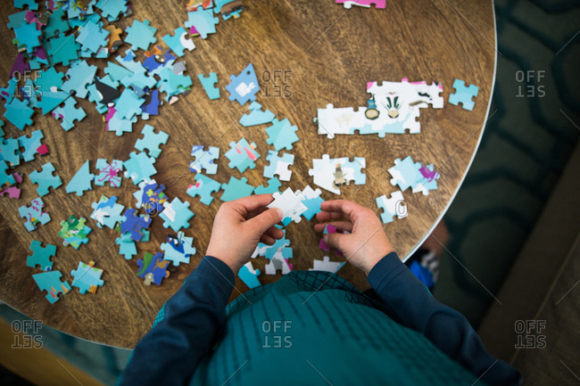 Overhead view of child putting puzzle together