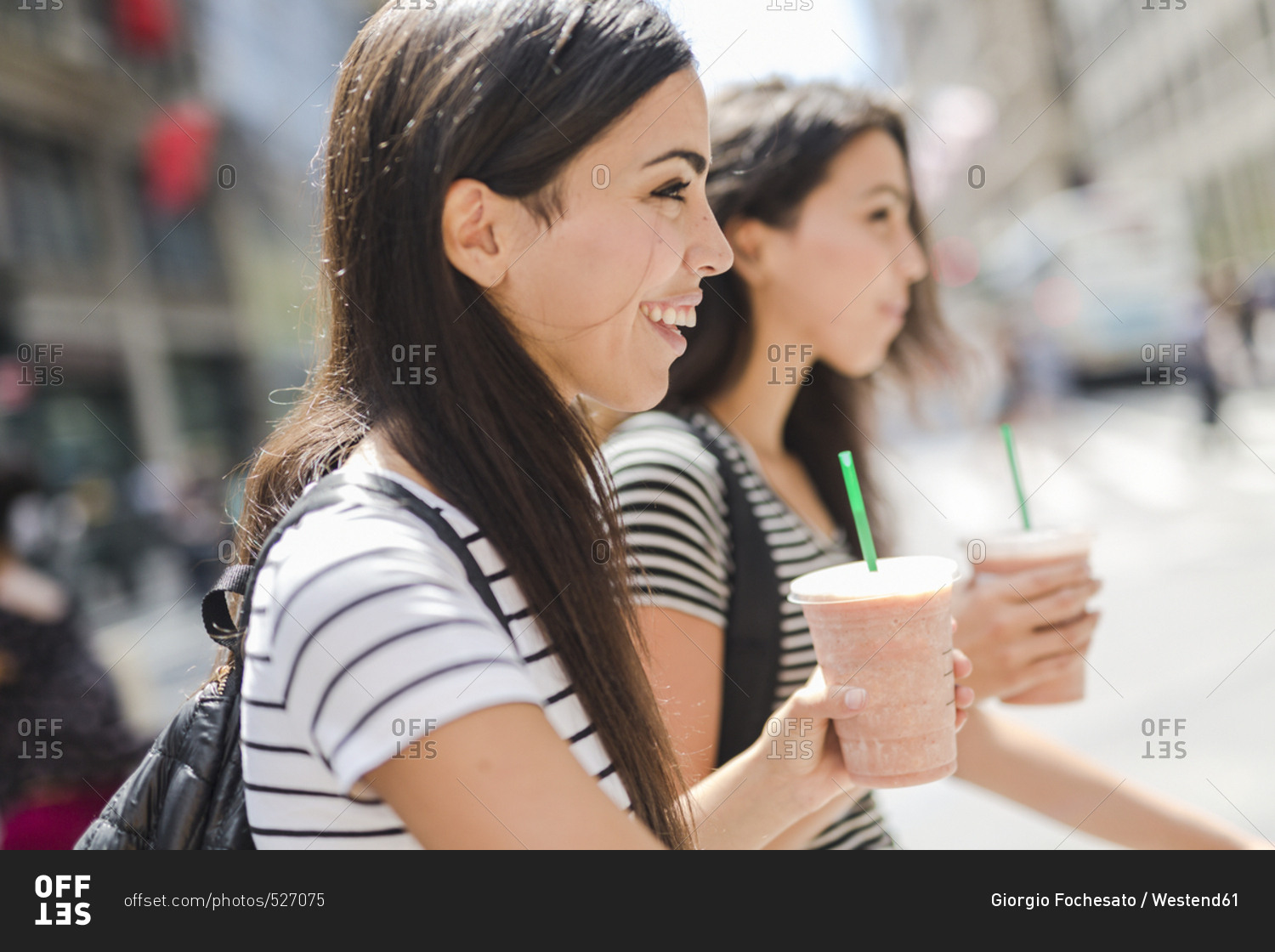 USA- New York City- two happy twin sisters on the go in Manhattan with takeaway drink