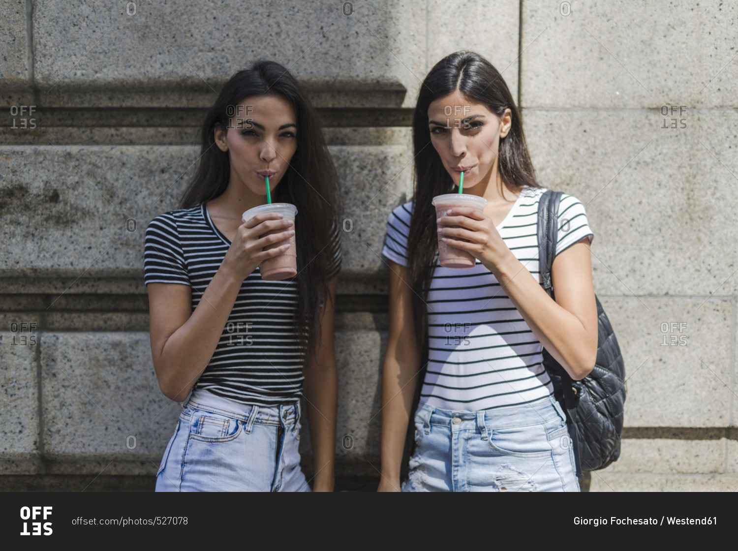 Two twin sisters having a takeaway drink