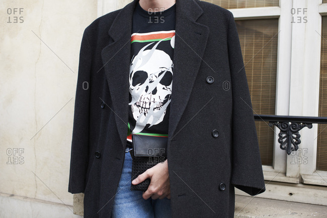 Young adult wearing skull motif t shirt, coat over shoulders