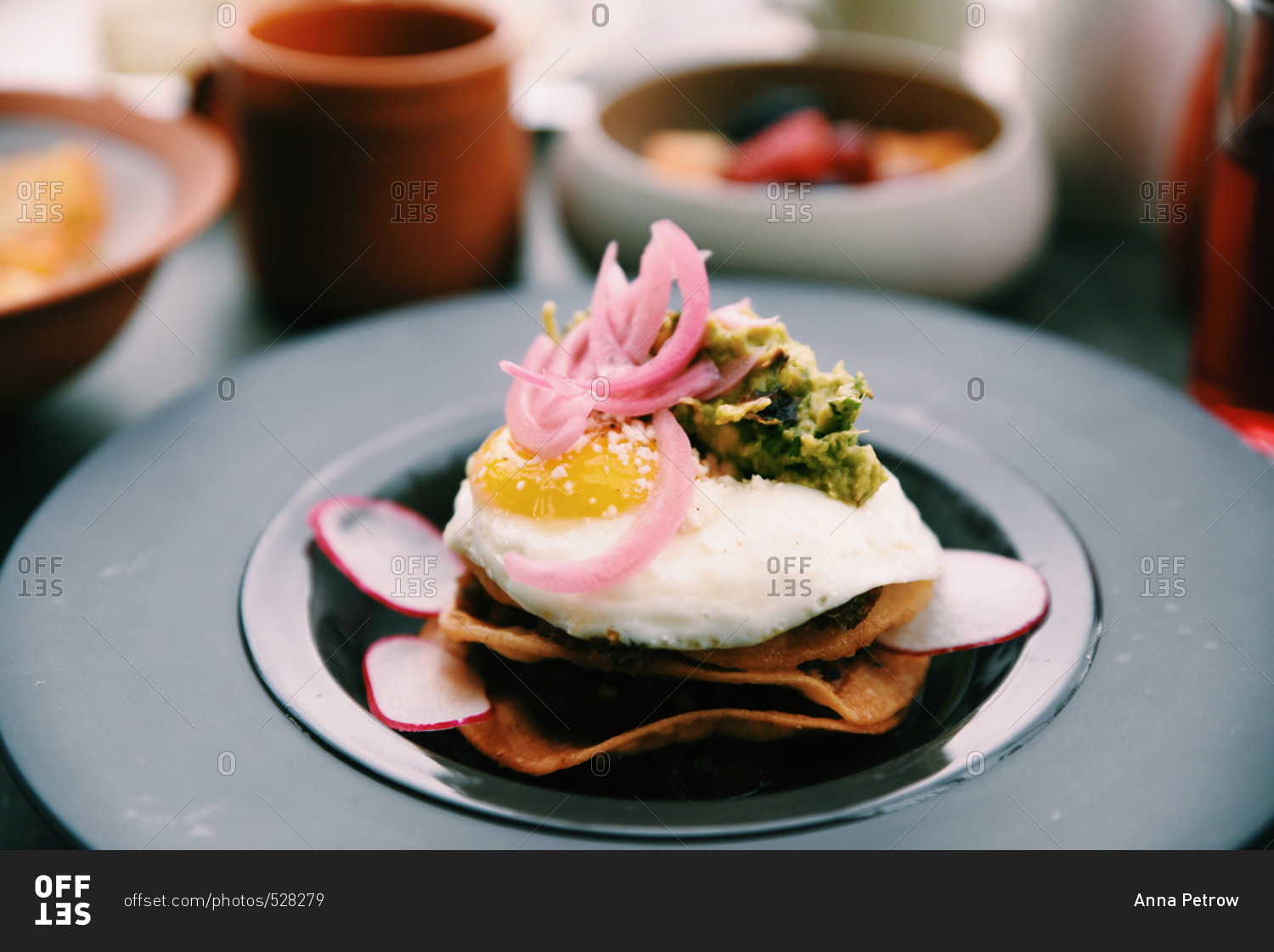 Fried tortillas topped with fried egg, guacamole and pickled onions