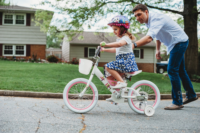Father helping his daughter learn to ride a bicycle