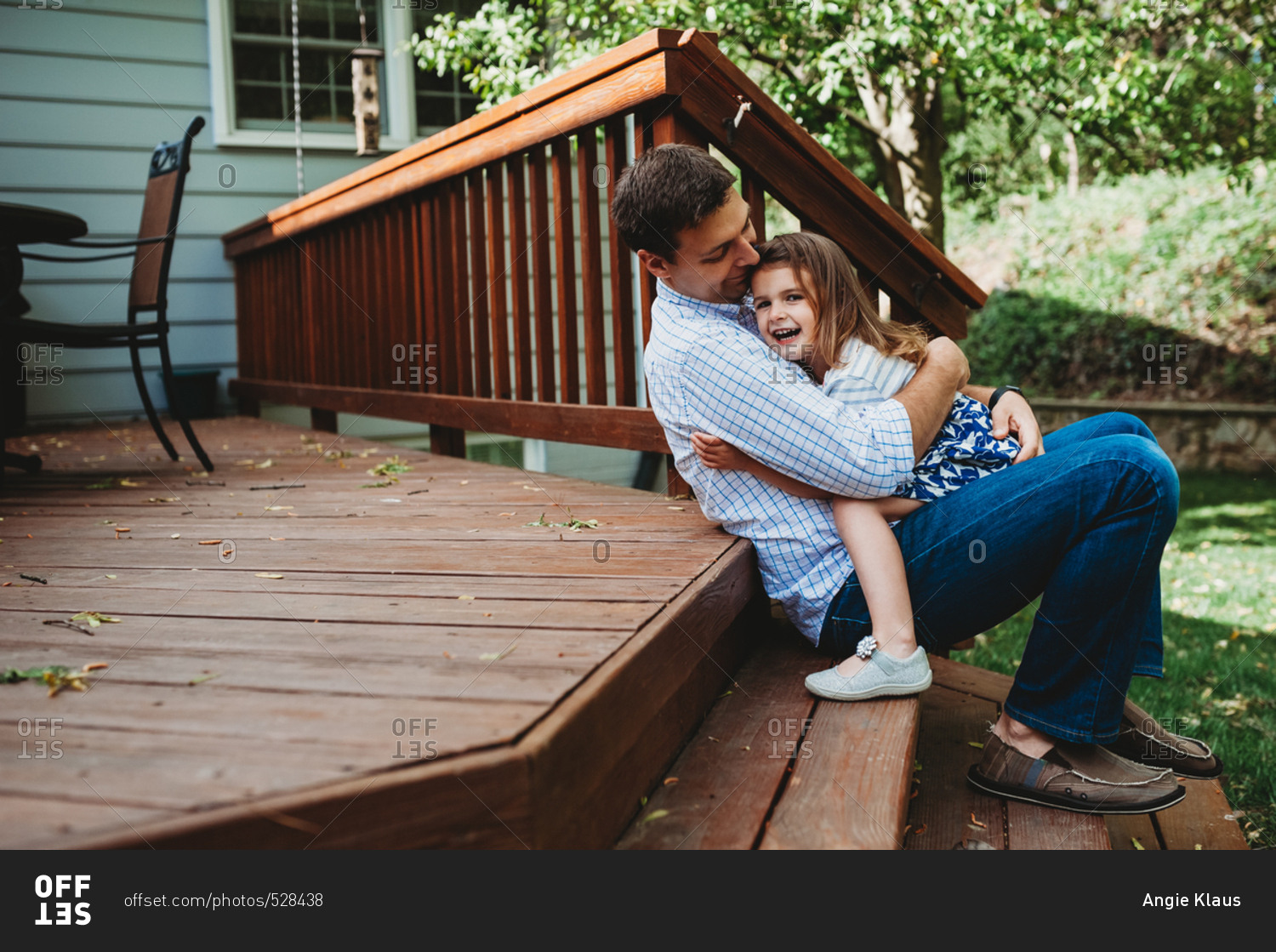 Father And Daughter Sitting On The Steps Of A Deck Hugging And Smiling 0572