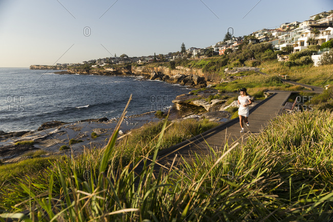 Woman running along coastal running path in Australia