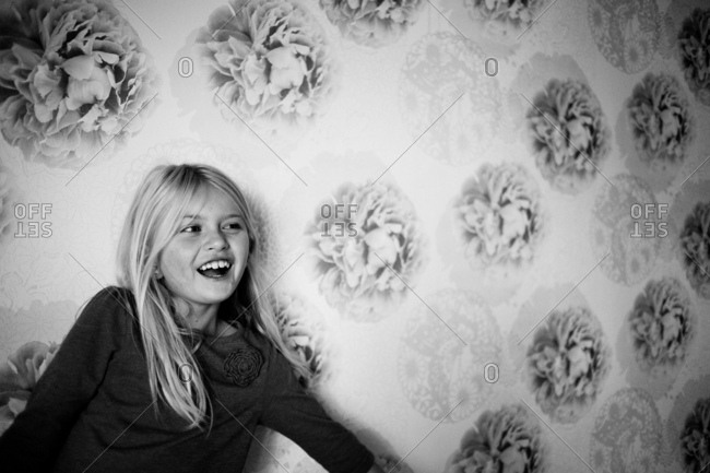Laughing girl against floral wallpaper