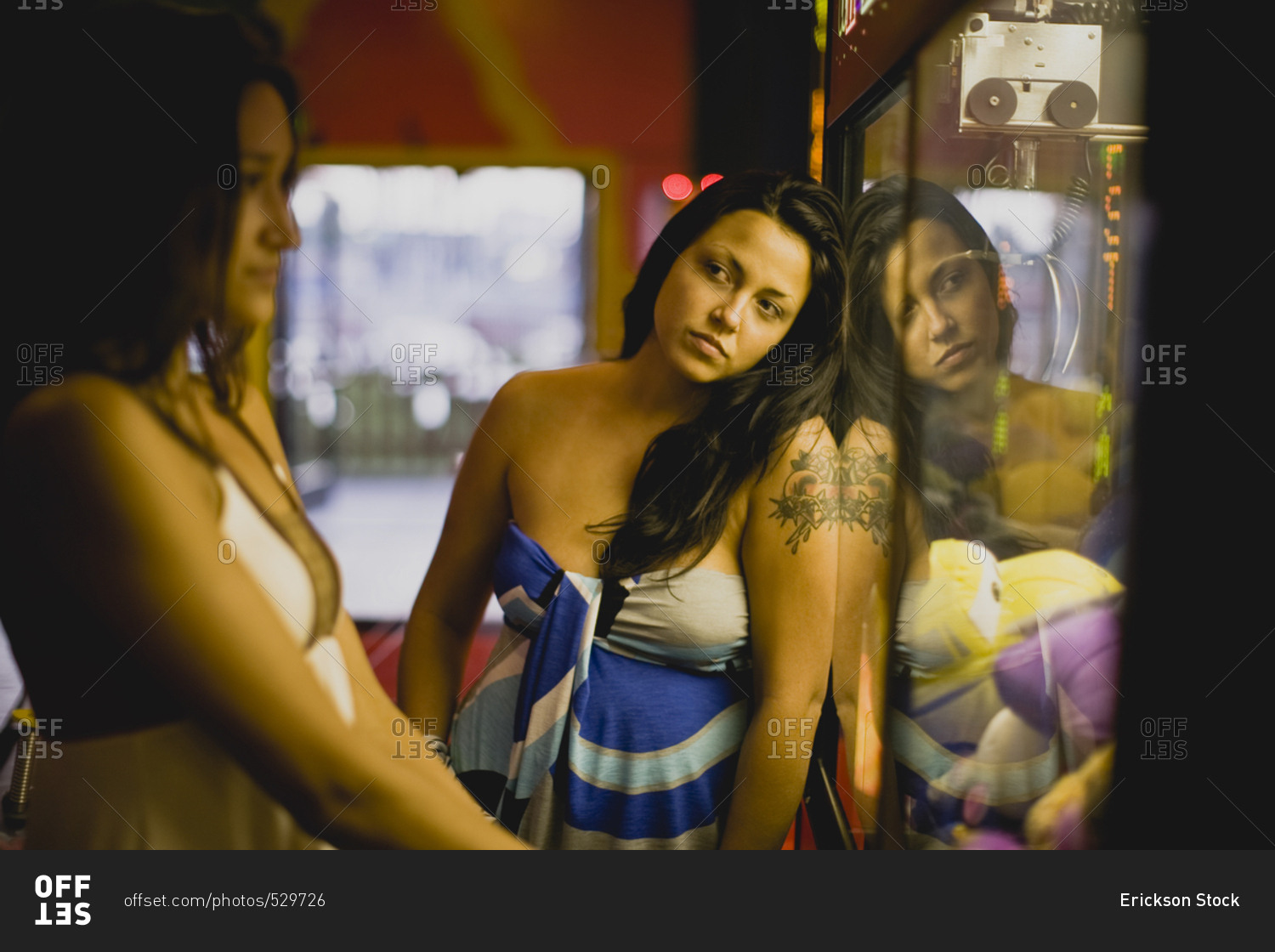 Young women playing the claw machine at an arcade