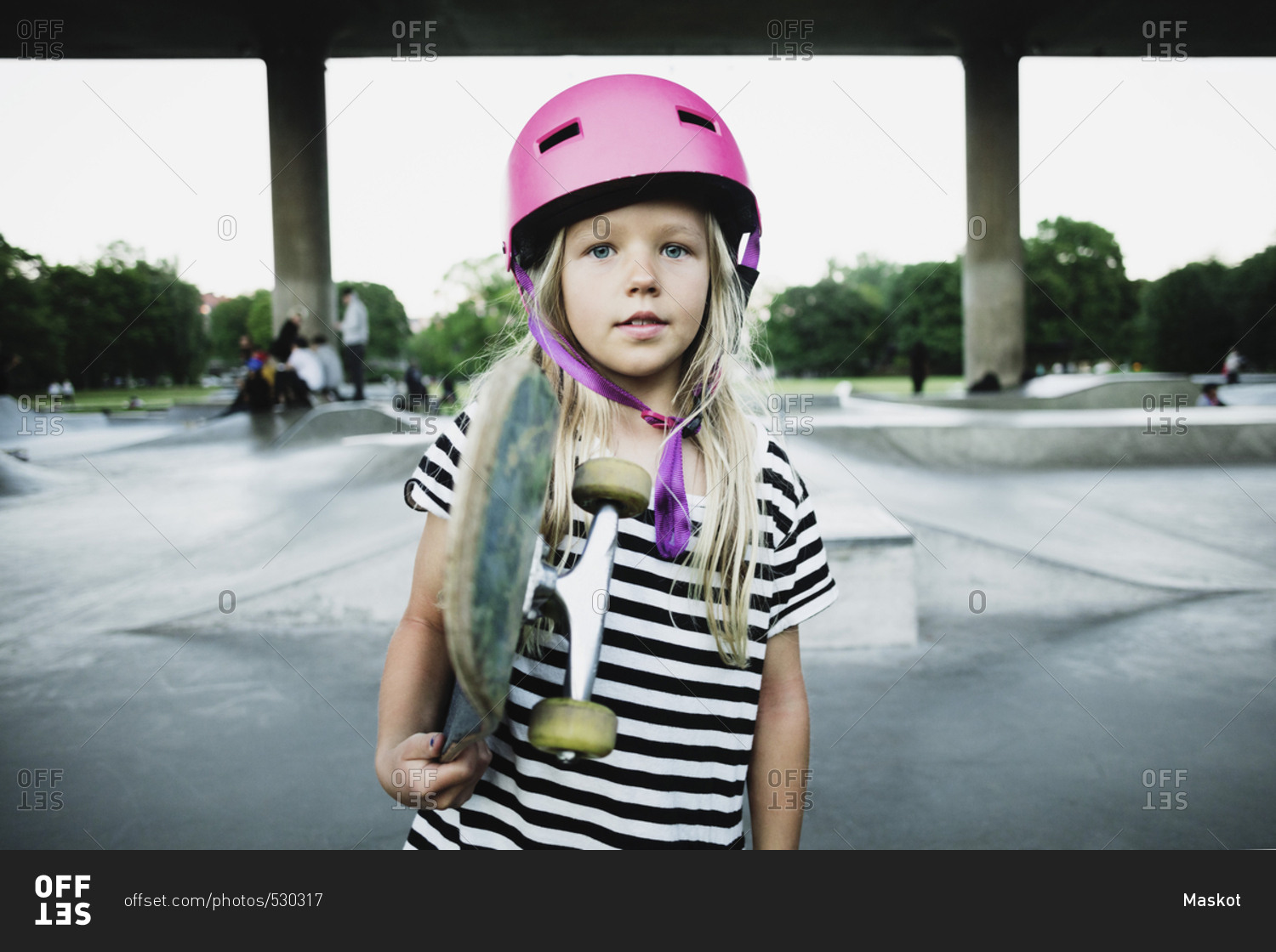 Portrait of girl holding skateboard while standing at park