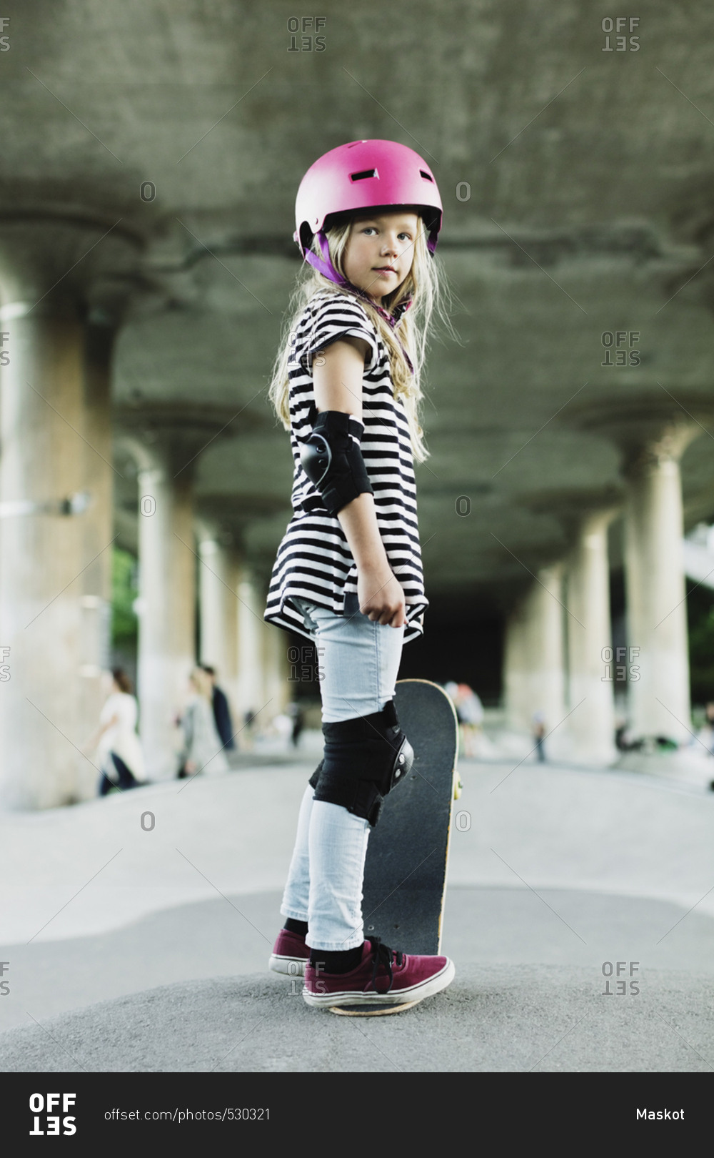 Full length of confident girl standing with skateboard at park