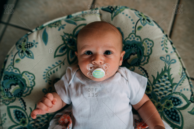 Baby boy with a pacifier in a blue patterned bouncy seat