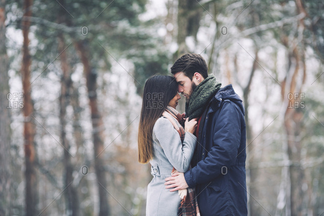 Couple romancing while standing in forest during winter