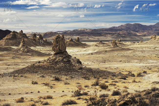 Scenic view of arid landscape against cloudy sky