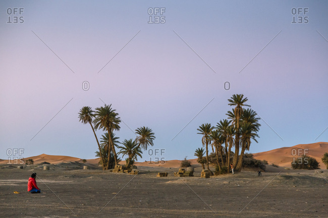 People riding camels crossing the Erg Chebbi sand dunes, Sahara Desert, Merzouga, Morocco.