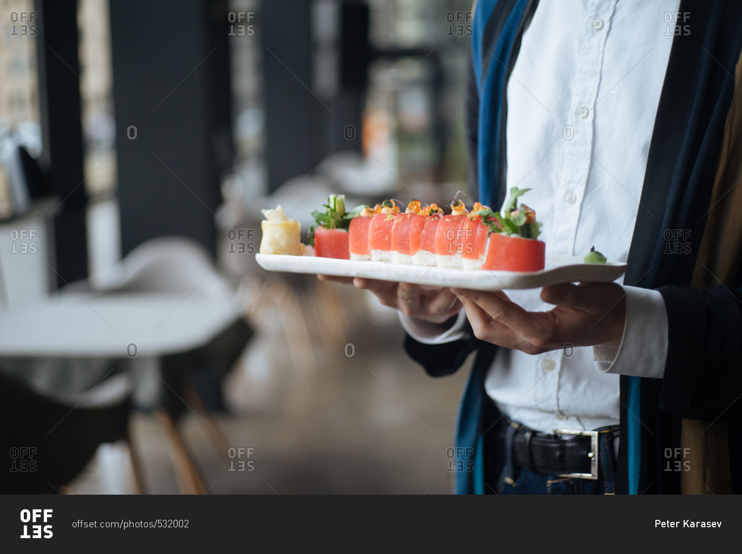 Server carrying dish with tuna rolls in a restaurant