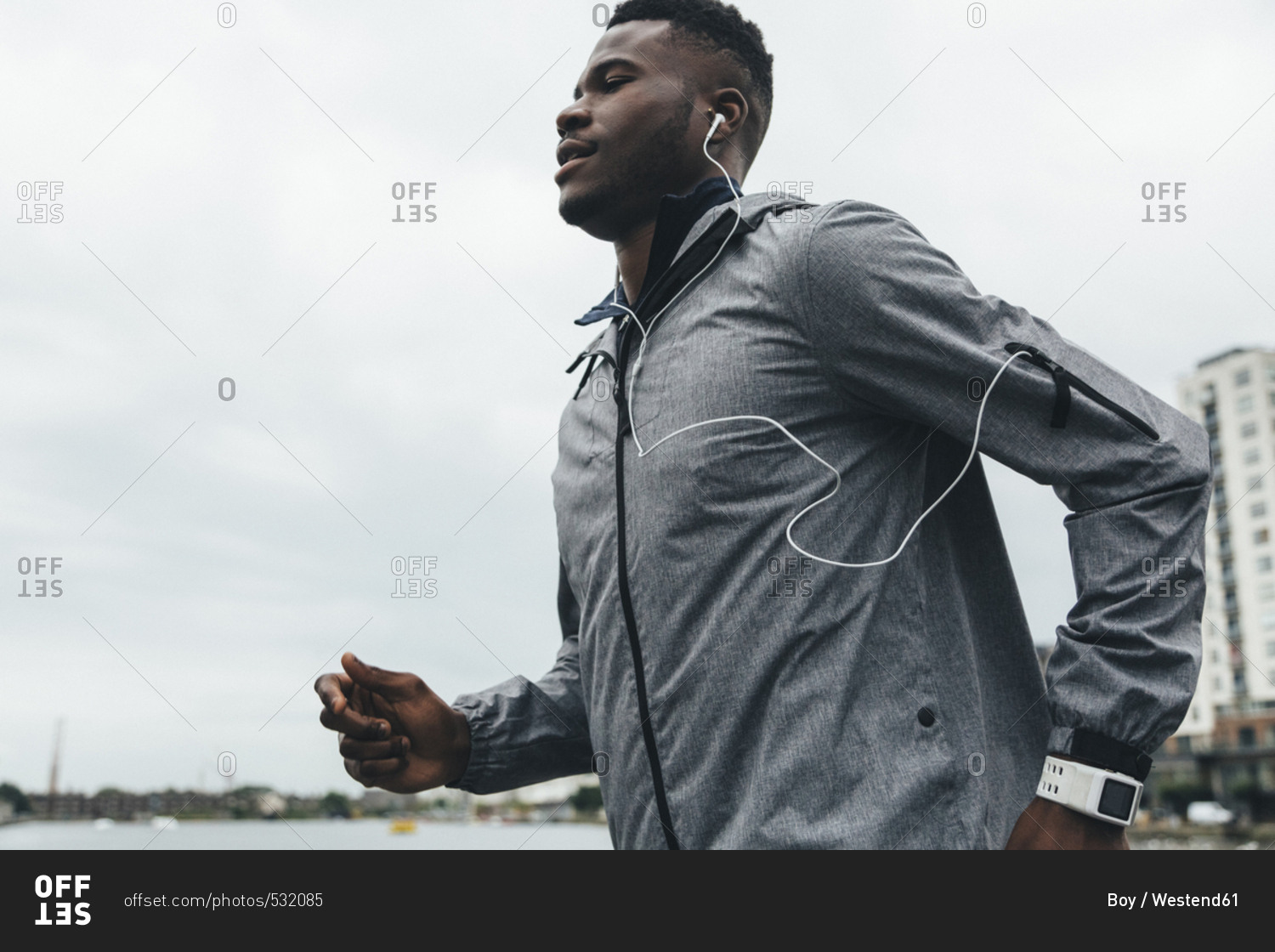Young man running with ear buds and smart watch