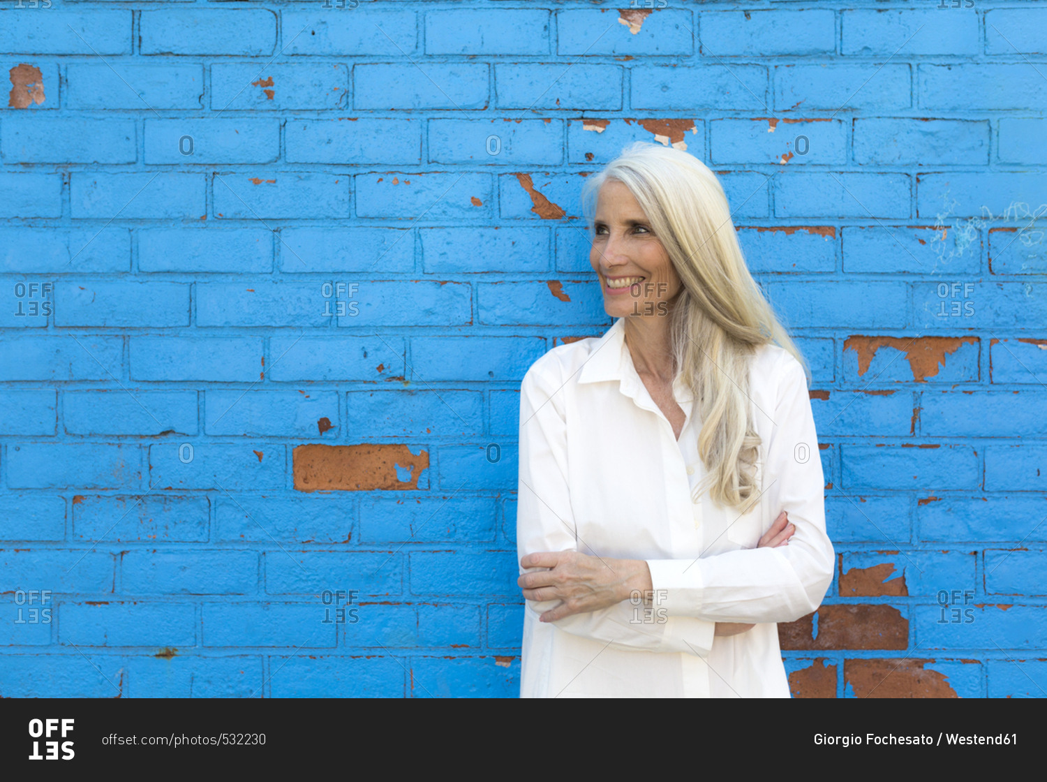 Smiling mature woman standing in front of light blue wall