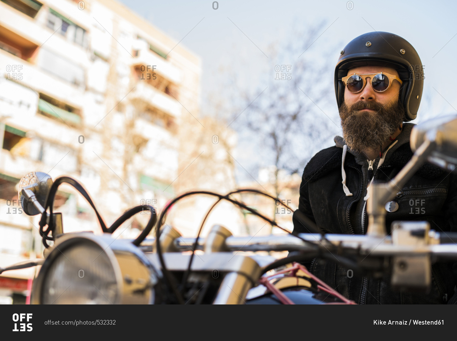 Portrait of bearded biker wearing helmet and sunglasses sitting on his motorcycle