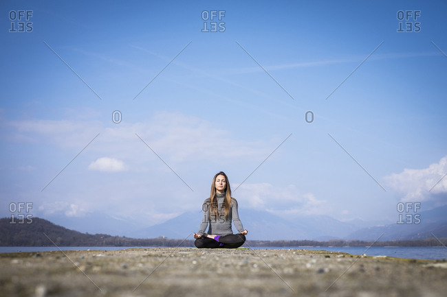Woman practicing yoga on a pier at a lake