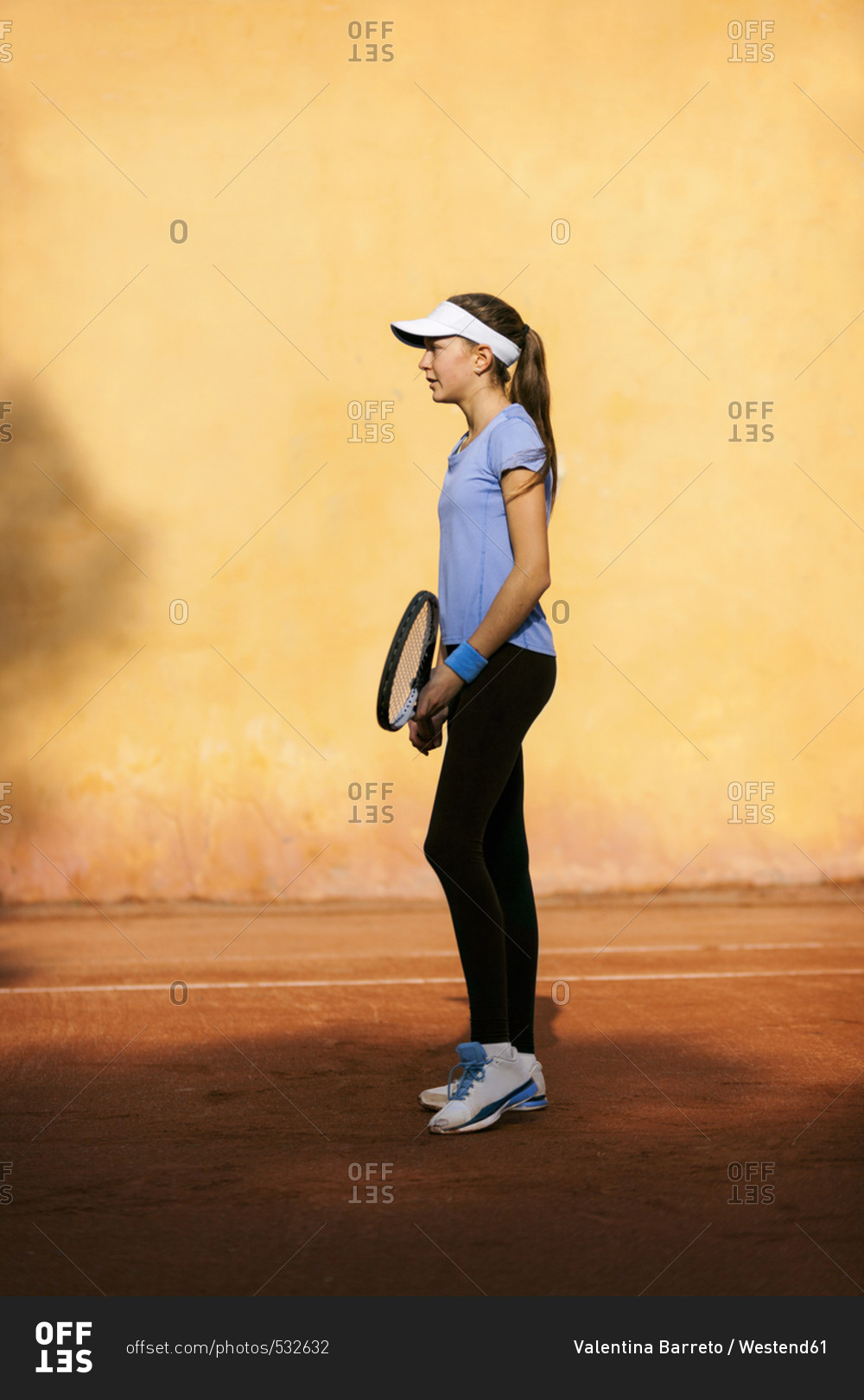 Teenage girl standing on tennis court