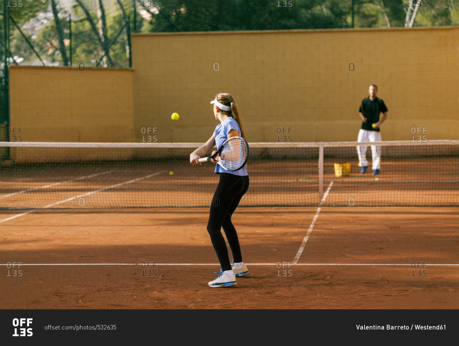 Teenage girl training tennis with her teacher