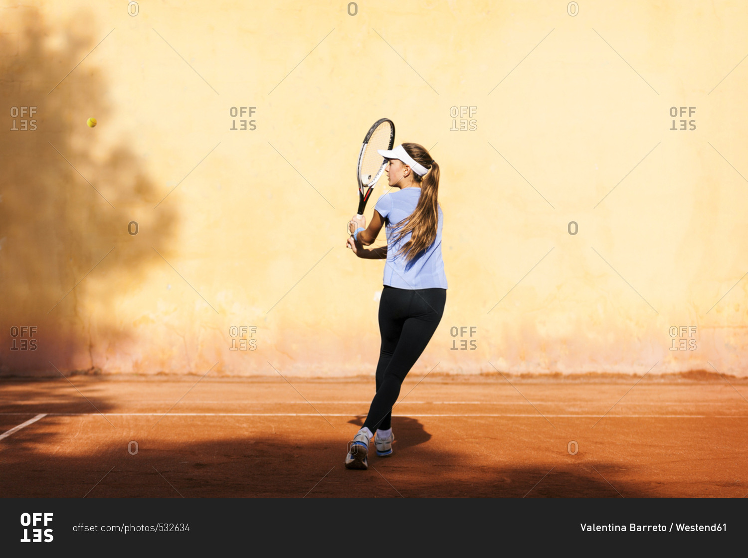 Teenage girl playing tennis on court