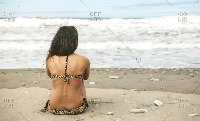 Woman taking off her shirt to reveal a bikini swimsuit top stock photo -  OFFSET