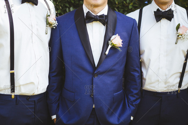 Groom and groomsmen in blue formalwear with pink flowers