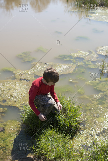 Young boy playing on patch of grass in a river