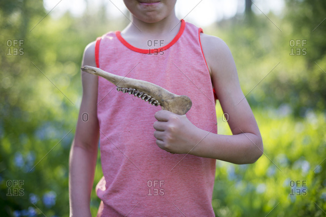 Child holding dead animal's jaw bone