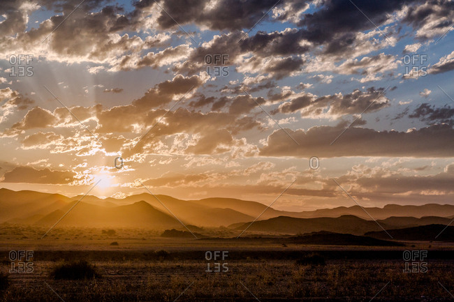 Sun rising over distant mountains and desert at the Hoanib Skeleton Coast, Namibia