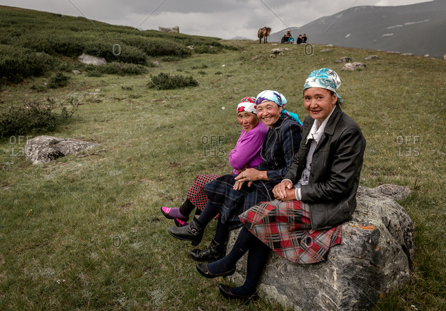 Altai Mountains, Mongolia - July 18, 2016: Three Kazakh women sitting on rock