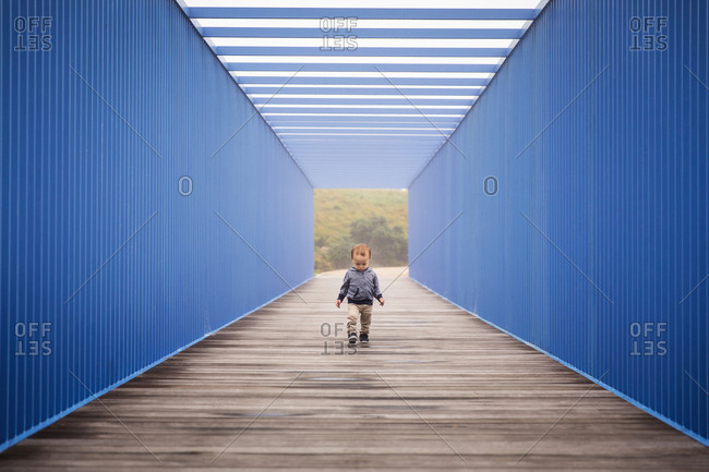 Toddler boy walking on boardwalk