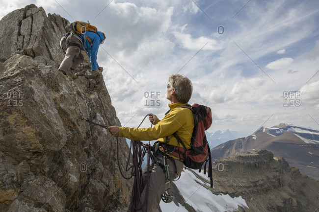 Mountaineer belays teammate on summit ridge