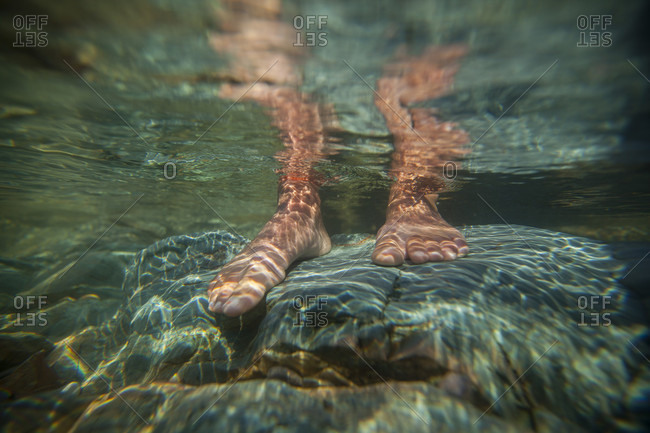 Underwater View Of Two Feet Standing On A Rock At Lake Pend Oreille, Idaho