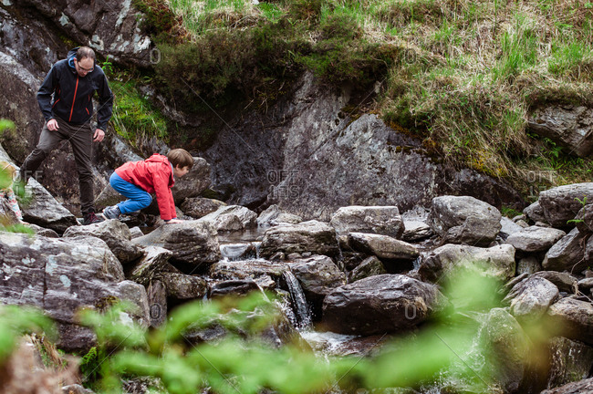 Man and boy climbing over stones