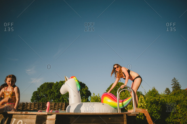 February 4, 2017 - Dordogne, France: Woman climbing on a unicorn float in above-ground pool