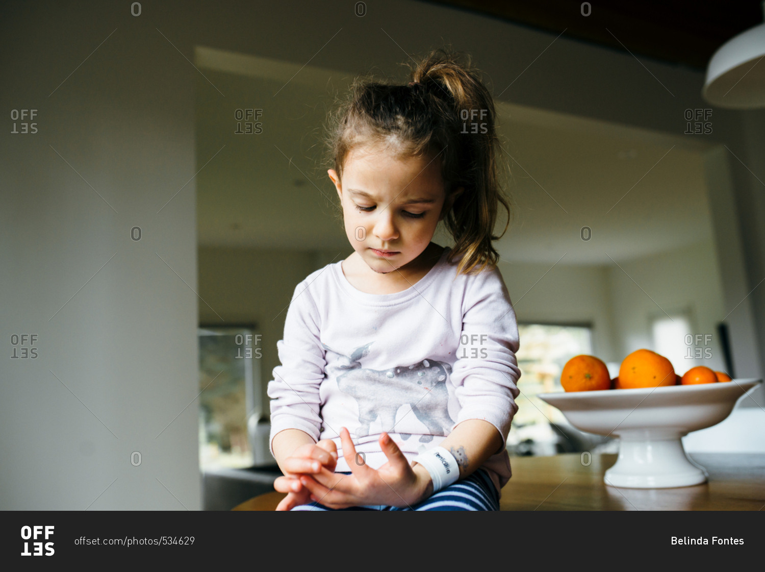 Young girl with fresh stitches sitting on table by oranges